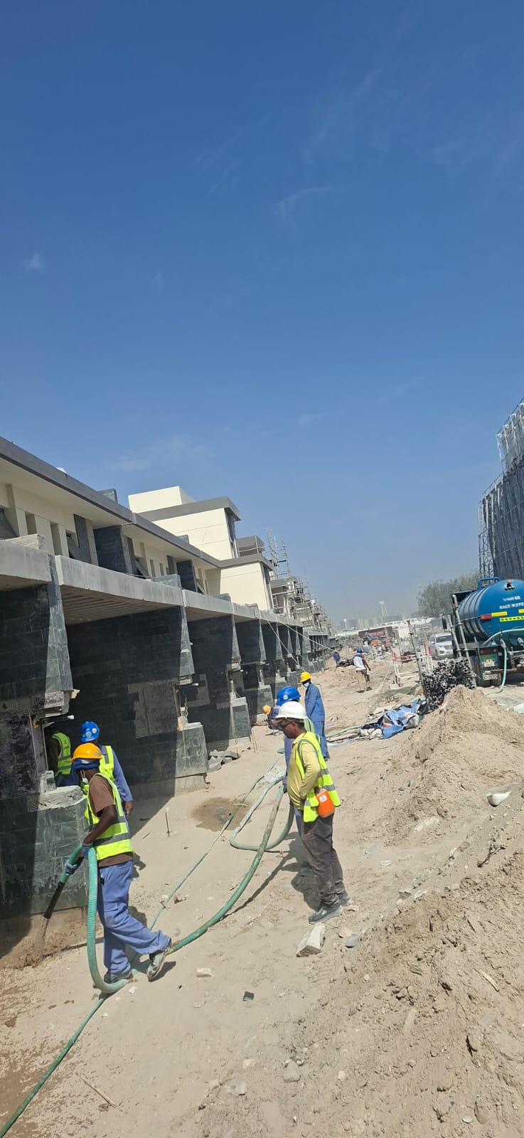Villa community under construction with stone cladding and workers on site